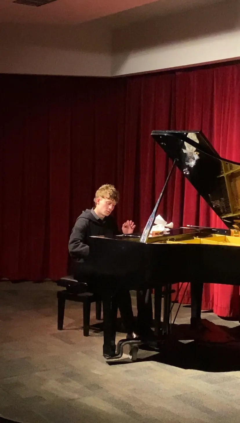 Student performing on stage at a piano recital
